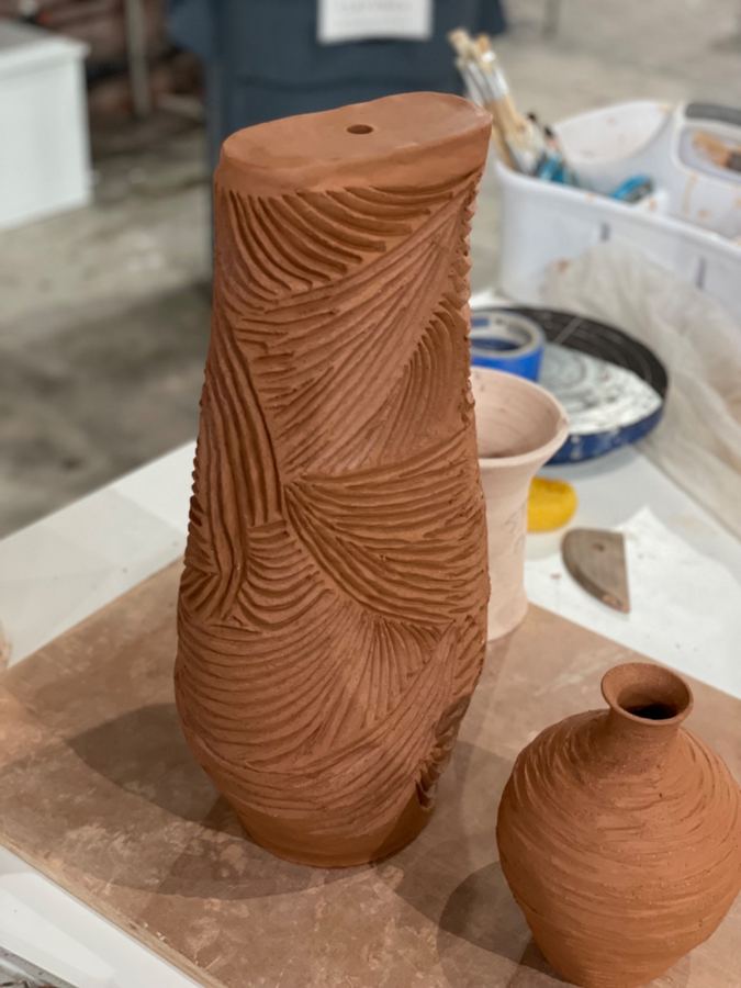 Raw terracotta lamp body with hand-carved lines in studio